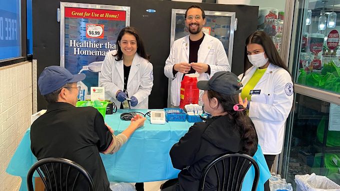 Orland Pharmacy pharmacists checking blood pressure for customers at a table in the store